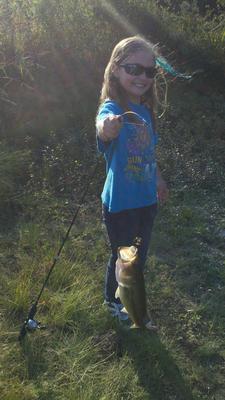 Happy Girl with a Largemouth Bass Caught from a Local Pond